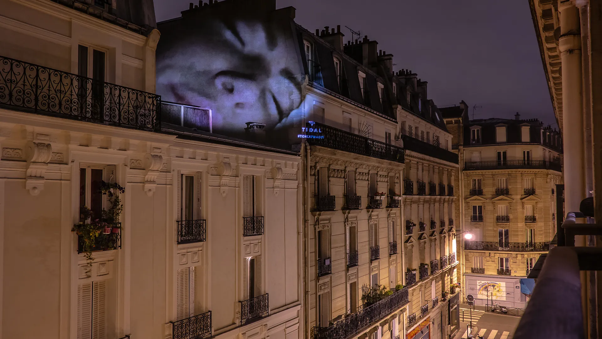 Public parisien assistant à une projection monumentale de nuit lors d’une intervention artistique urbaine.