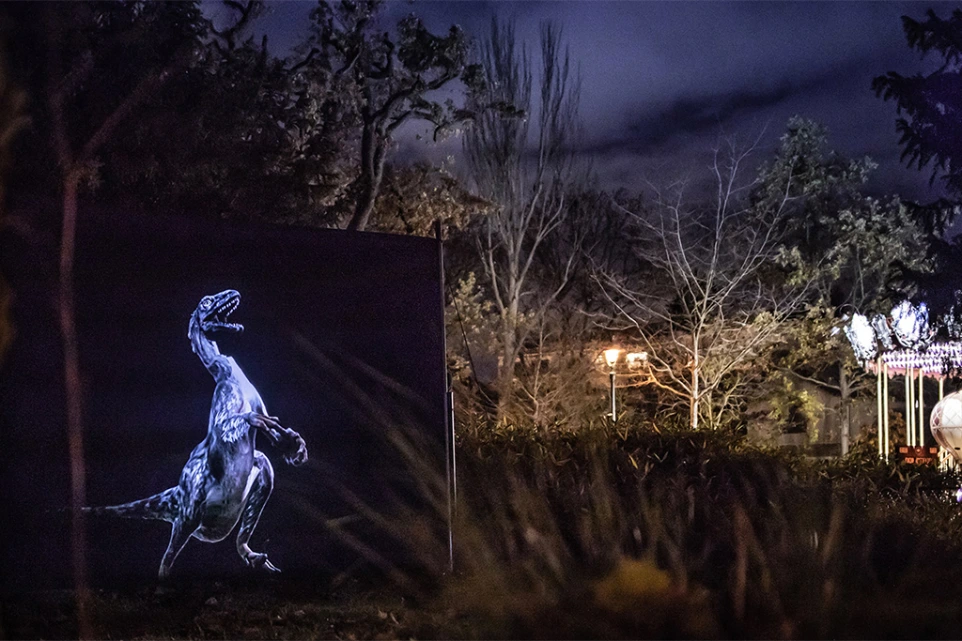 Dinosaure préhistorique apparaissant dans un parc nocturne – Prehistoric Safari, installation artistique en extérieur