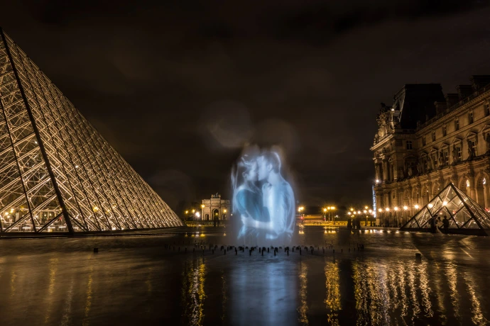 Projection lumineuse d’un couple s’embrassant dans la cour du Louvre, face à la pyramide – Le Baiser, art numérique