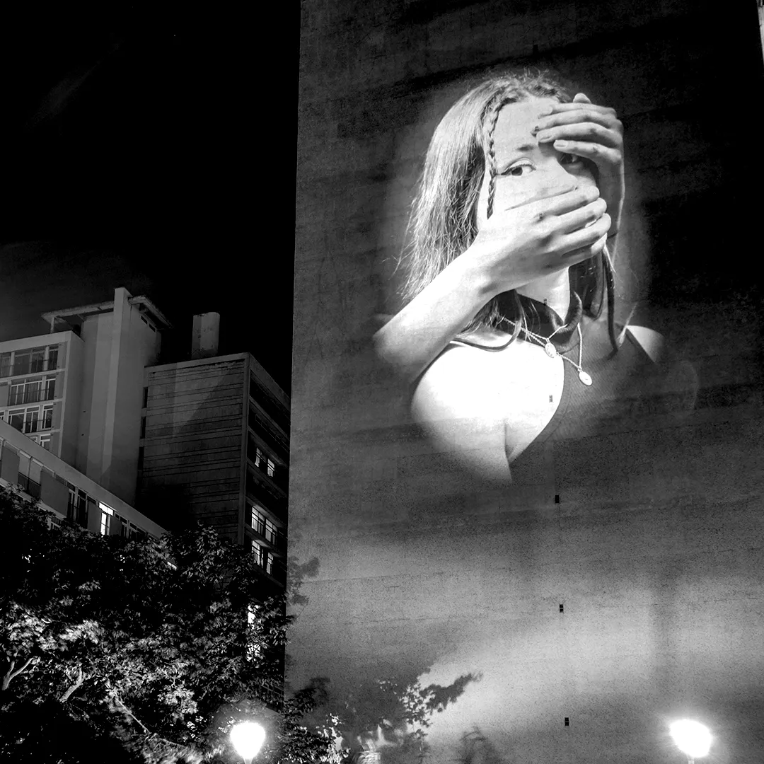 Projection monumentale dénonçant le silence imposé, la censure et la domination des images dans l’espace urbain.